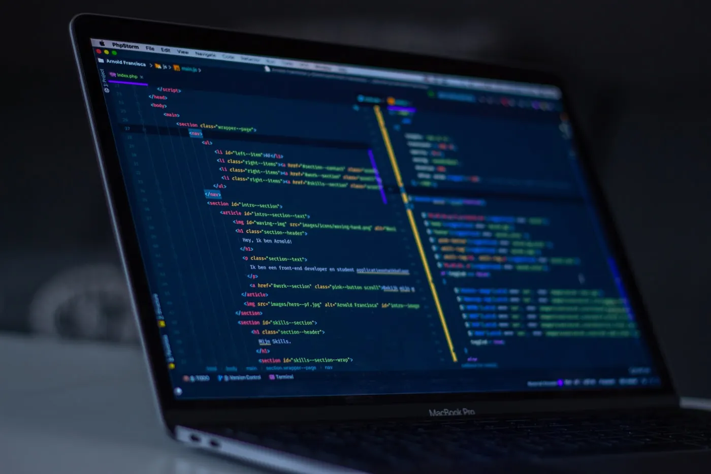 Laptop displaying source code in a dark editor.