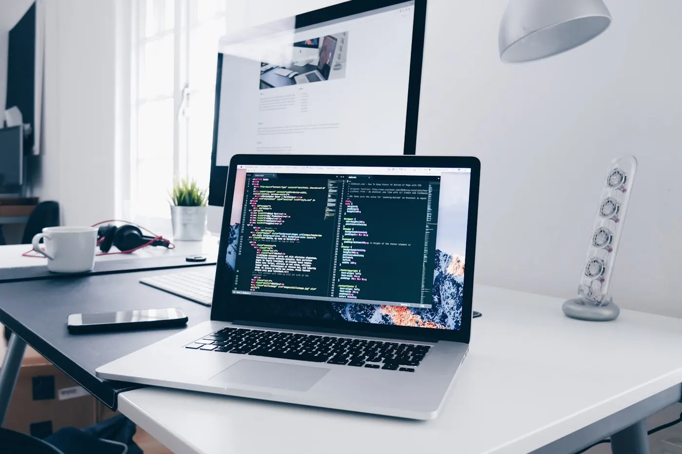 Laptop on a desk showing application source code.